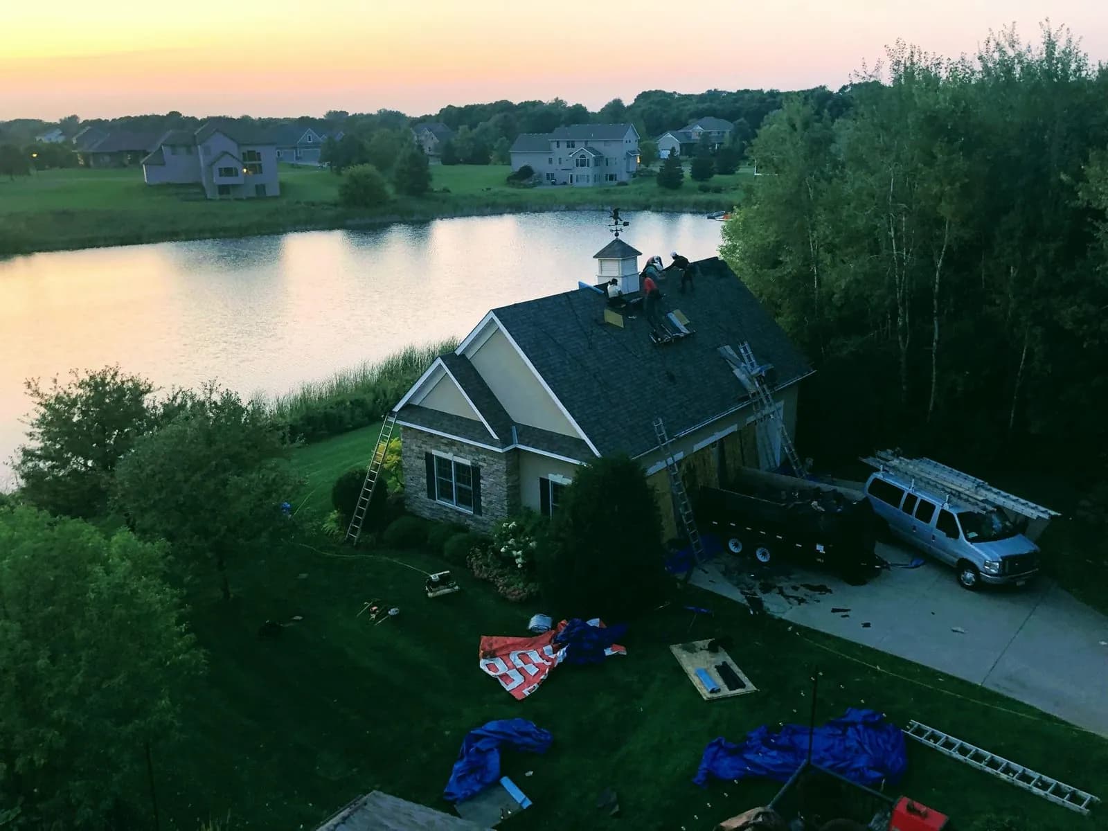 Aerial view at sunset of a waterfront home with a newly completed gray architectural shingle roof
