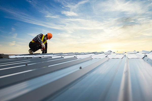 Commercial roofer wearing safety gear installs a commercial roof in Crosslake, MN